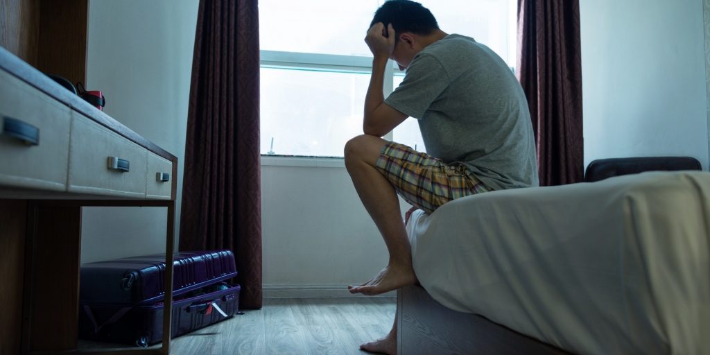 Man sitting on bed with head in hands