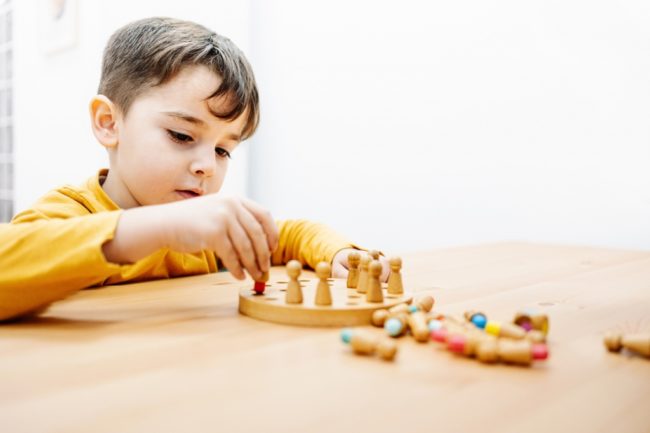 Little kid playing a board game during education therapy