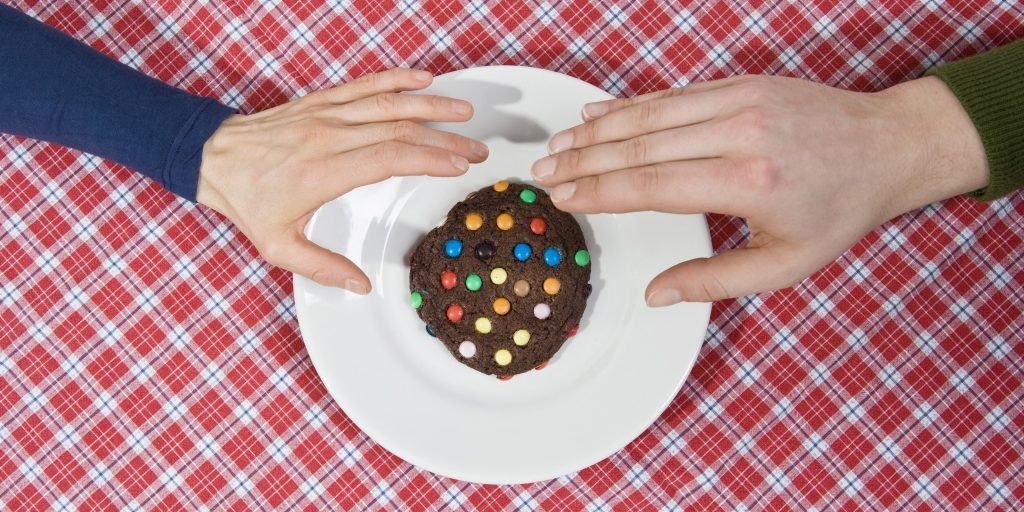 Two hands reaching for a cookie