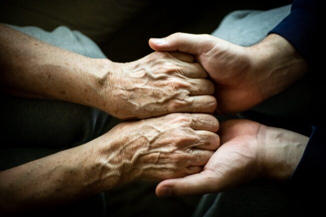 Close up of son holding his mothers hands